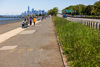 Volunteers paint benches along the Shore Parkway Greenway in Bay Ridge, Brooklyn, with the lower Manhattan skyline across the harbor, during Jalen's Eagle Scout project, May 16, 2026