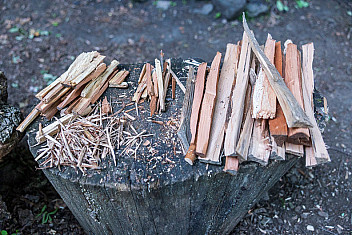 Wood shavings for tinder, thin split kindling and larger split fuel wood sorted by size on a chopping block, Camp Seton