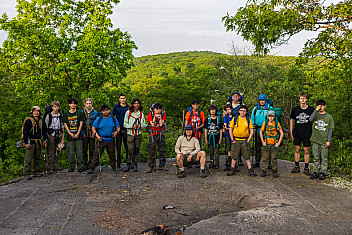 Troop 23 Brooklyn Scouts and leaders with their packs on a rock ledge near the Stockbridge Shelter, Harriman State Park, early on the last morning of a three-day trek, May 26, 2024