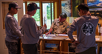 Togue Pond Gate — Baxter State Park Troop 23 Brooklyn checking in with a ranger at the Togue Pond gatehouse, the southern entrance to Baxter State Park, before riding up the gravel Park Tote Road, August 10, 2026