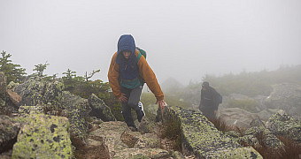 A scout climbing the boulder field above the treeline in cloud with visibility of about ten feet, the mountain invisible around him, Tuesday of Troop 23 Brooklyn's Adventure Trek, August 11, 2026