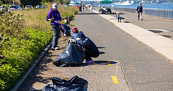 Volunteers bag weeds cleared from the edge of the Shore Parkway Greenway in Bay Ridge, with the Verrazzano-Narrows Bridge in the distance, during Jalen's Eagle Scout project, May 16, 2026
