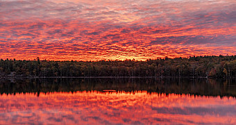 A red sunrise sky reflected in Crystal Lake, seen from the Lakeside Lean-Tos at Ten Mile River Scout Camps, October 2025