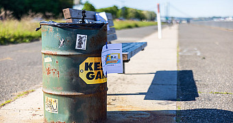Trash Can Before Repainting on the Shore Parkway Greenway A worn green trash can on the Shore Parkway Greenway in Bay Ridge before repainting, with the Verrazzano-Narrows Bridge in the distance, May 16, 2026