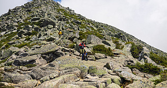 The boulder field of the Hunt Spur seen straight up the fall line, three scouts strung out at different heights across it giving the scale, the ridge running up against cloud, Tuesday of Troop 23 Brooklyn's Adventure Trek, August 11, 2026