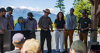 National Park Service rangers and guests cutting the ribbon at the tenth-anniversary ceremony of Katahdin Woods and Waters National Monument, which Troop 23 Brooklyn walked into on the morning of its service project, August 14, 2026