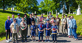 Scouts, Cub Scouts, leaders and parents gather on a road inside Green-Wood Cemetery, Brooklyn, before placing flags on veterans' graves, May 2025