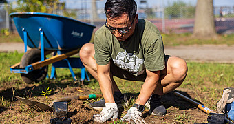 A volunteer in work gloves plants seedlings in Shore Road Park, Bay Ridge, during Ty's Eagle Scout project, September 28, 2025