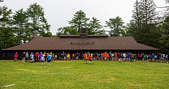 Scouts gather on the field in front of Jesse H. Metcalf Lodge, the dining hall of Camp Sandy Beach at Camp Yawgoog, Rhode Island, on a July morning in 2025