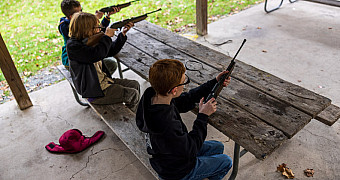 Scouts shooting BB guns from a covered pavilion at Camp Keowa, Ten Mile River Scout Camps, during the Halloween shooting sports weekend, October 2025