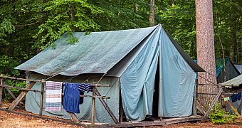 Platform Tent at Camp Yawgoog A canvas wall tent on a wooden platform, with towels drying on the rail, in a Camp Yawgoog campsite, Rhode Island, July 2024