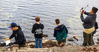 Scouts and an adult leader fishing from the rocky shore of Crystal Lake by the Lakeside Lean-Tos, Ten Mile River Scout Camps, October 2025
