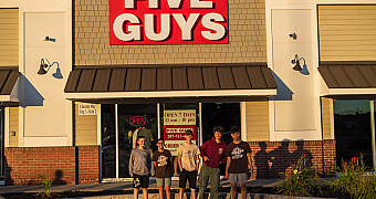 Five scouts lined up under the Five Guys sign in Augusta, Maine, in low evening light on the drive south from Katahdin Woods and Waters, Friday of Troop 23 Brooklyn's Adventure Trek, August 14, 2026